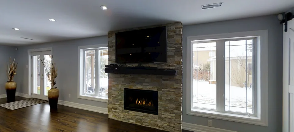 The stone fireplace and the walkout doors, in a finished Harmony basement in Aurora, captured in 360 degrees