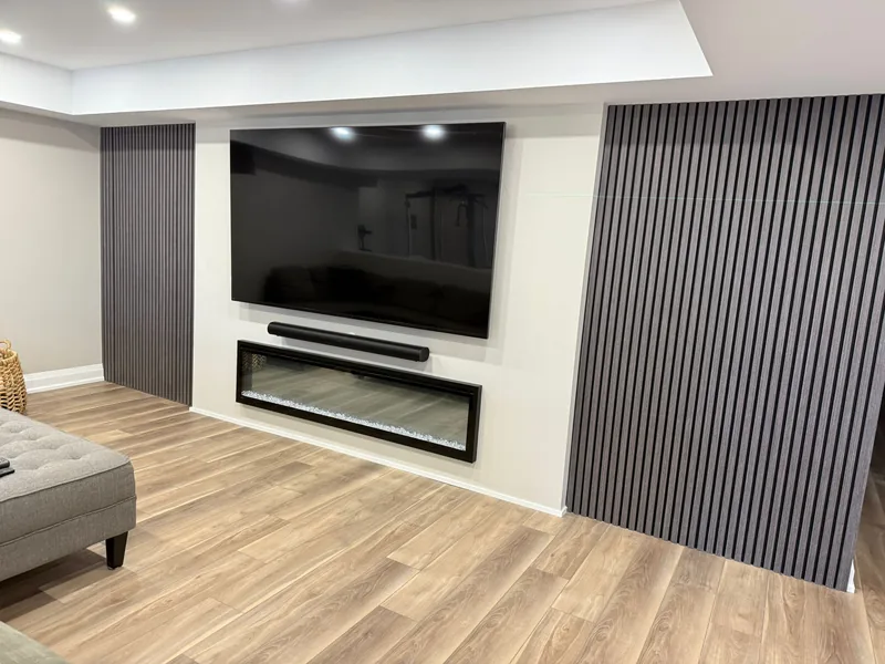 Finished basement Aurora: the TV and electric fireplace wall between two slat panels — built in East Gwillimbury