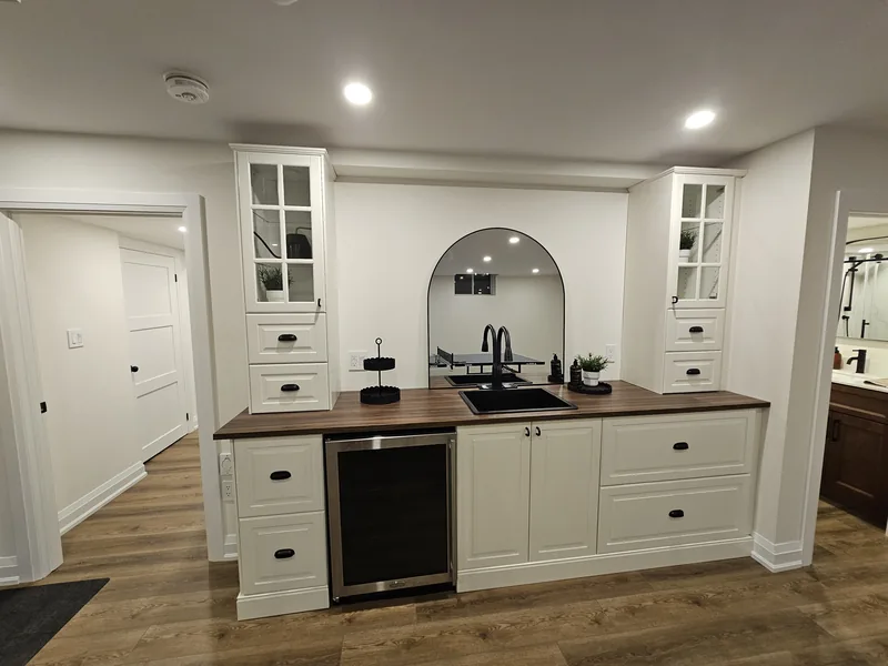 Finished basement wet bar Brampton: arched niche and bar fridge; cabinetry by the homeowner, plumbing rough-in by Harmony Basements — built in Ancaster, Hamilton