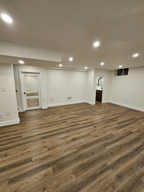 Basement finishing Georgetown: the family room with engineered vinyl plank flooring, a bulkhead and a glass-panel door, by Harmony Basements — built in Hamilton