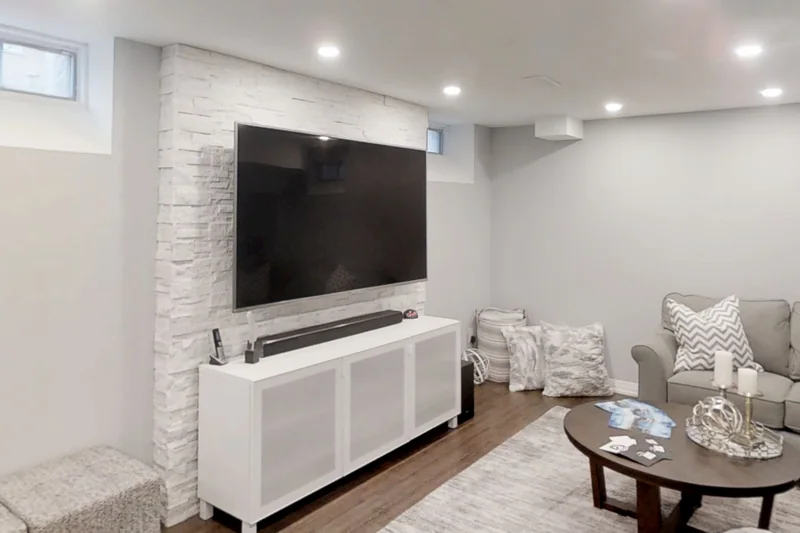 The stone-clad TV wall and the sectional in a finished Harmony basement