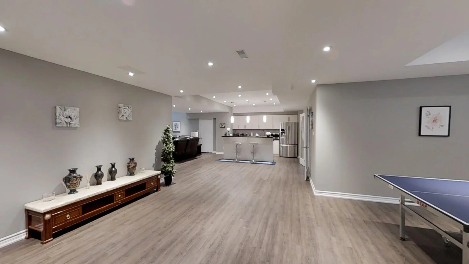 The same Vaughan basement finished: an open room with a games area and the kitchen beyond