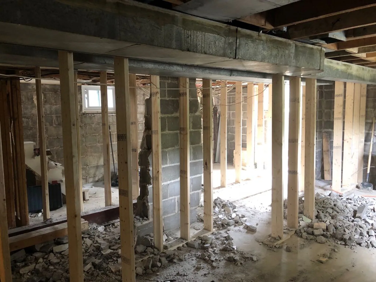 Temporary shoring walls carrying the floor above while the load-bearing block wall is taken out of a Toronto basement