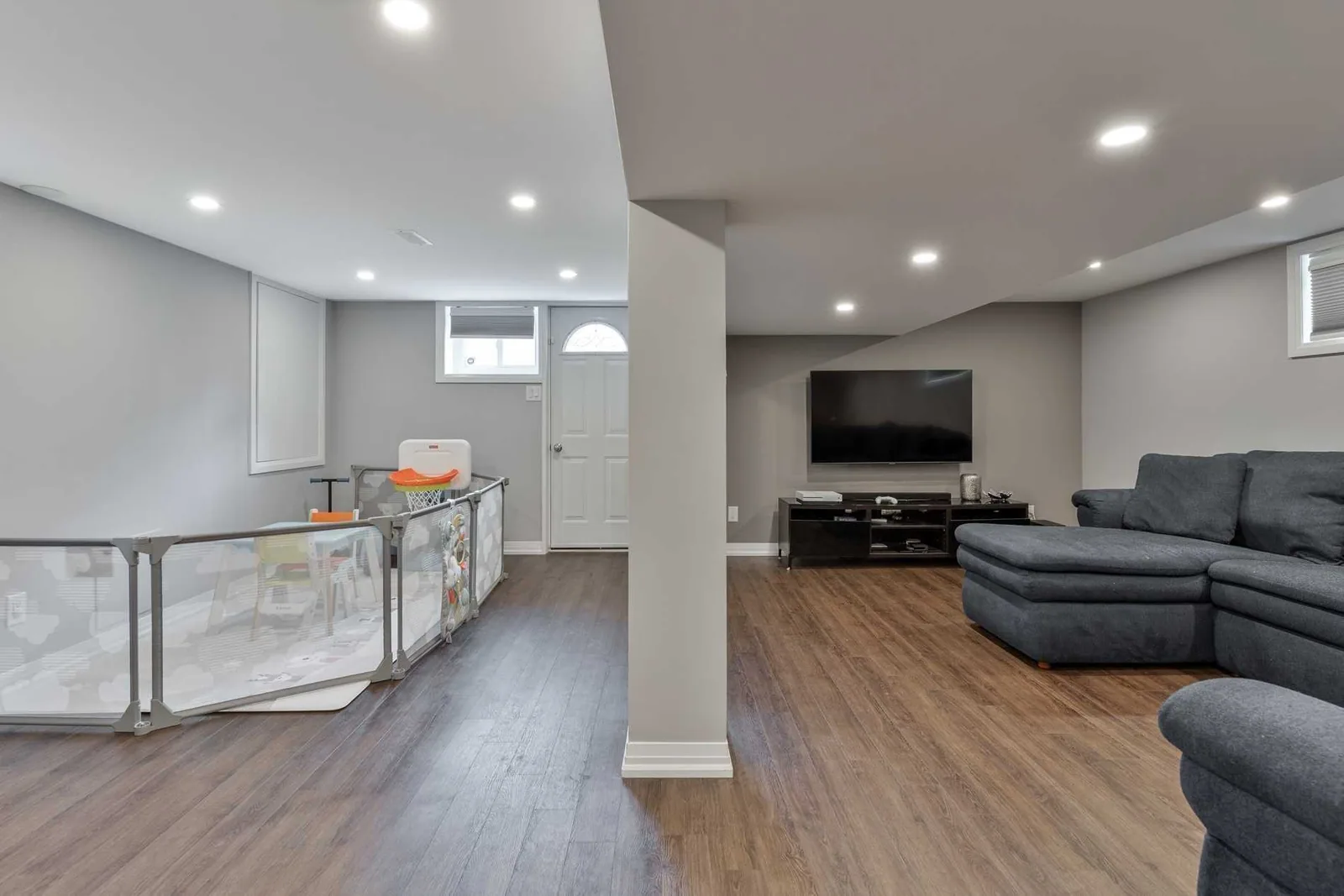 The full span of the finished basement, from the stair to the far end, with the bearing wall gone