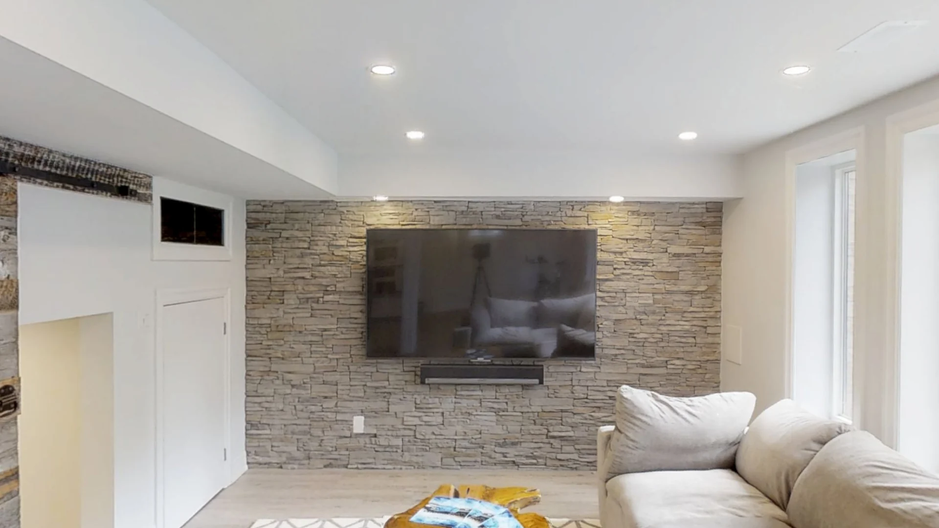 A finished Harmony walkout basement: the stacked-stone TV wall, the rustic barn door and the sectional
