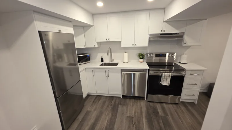 Basement finishing King City: the white shaker kitchen with its stainless appliances — built in Woodbridge