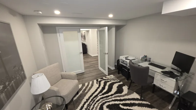 Basement renovation Etobicoke: the office with its frosted-glass doors open to the family room — built in Woodbridge