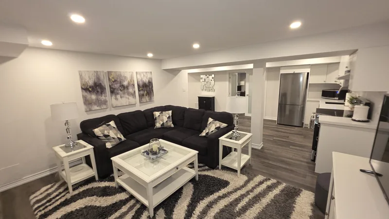 Finished basement Thornhill: the living room, with the kitchen and the frosted French doors beyond — built in Woodbridge