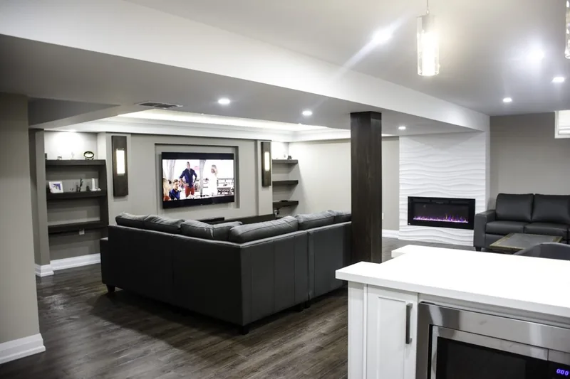 Luxury finished basement in Toronto: media wall with a linear fireplace and a black sectional, from the walkthrough film