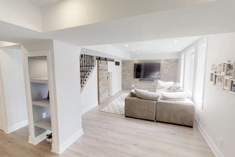 A finished Harmony walkout basement in Oakville with a natural stone accent wall, a barn door and a custom-built sauna, in the 3D tour