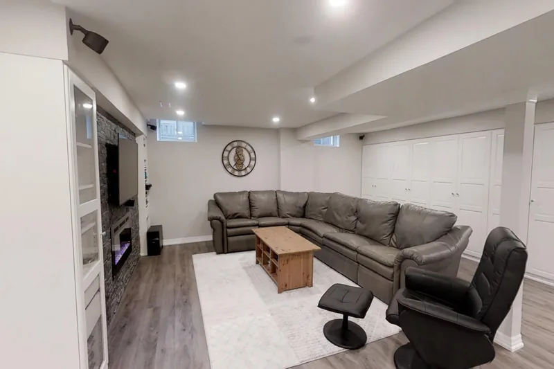 A finished Harmony basement in Burlington: a grey sectional facing a media wall with a fireplace, in the 3D tour