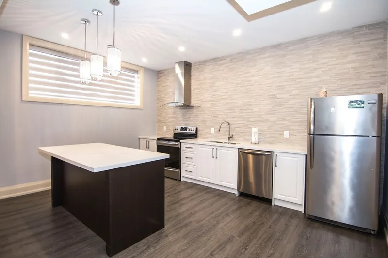 Custom finished basement in Woodbridge: white kitchen with an island and a range hood, from the walkthrough film