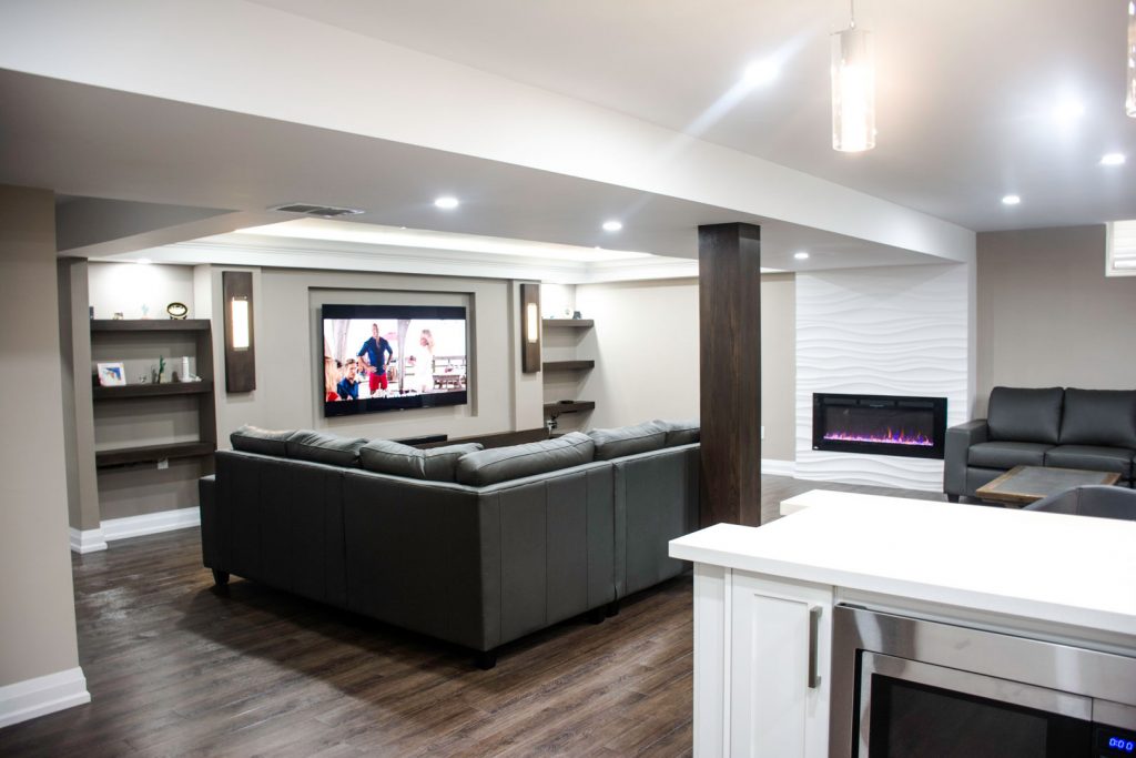 Basement renovation in Toronto: the living area and its plastered fireplace wall, by Harmony Basements
