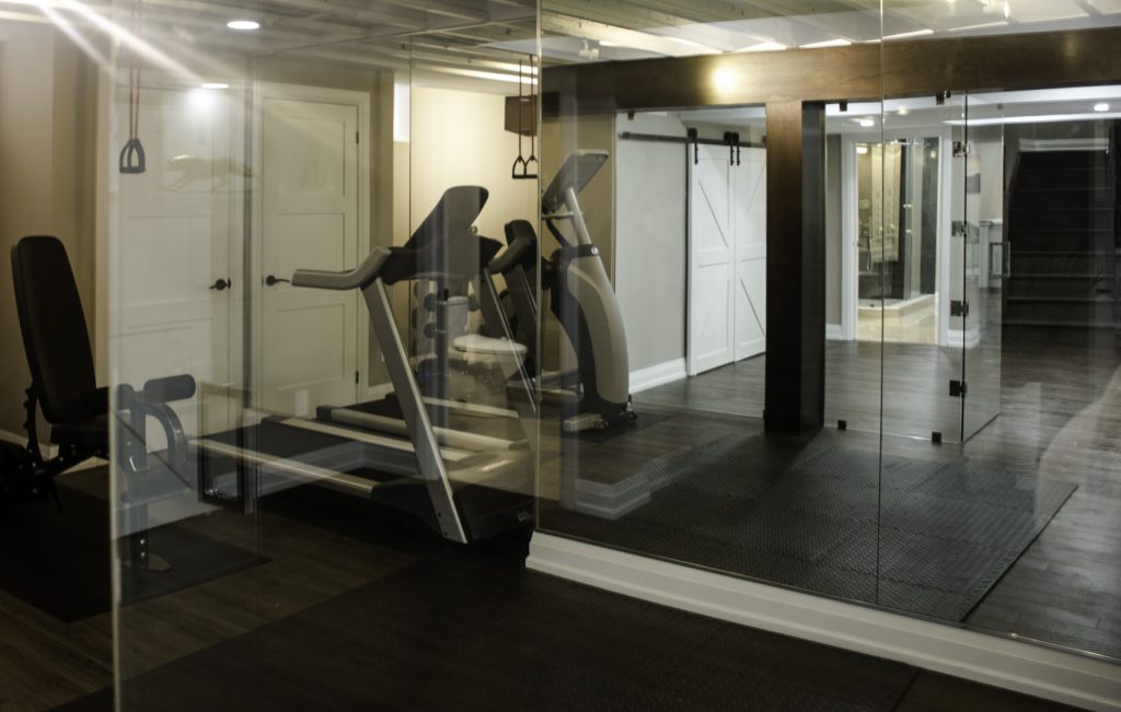 Basement remodeling in Toronto: the home gym behind its glass partition wall, by Harmony Basements