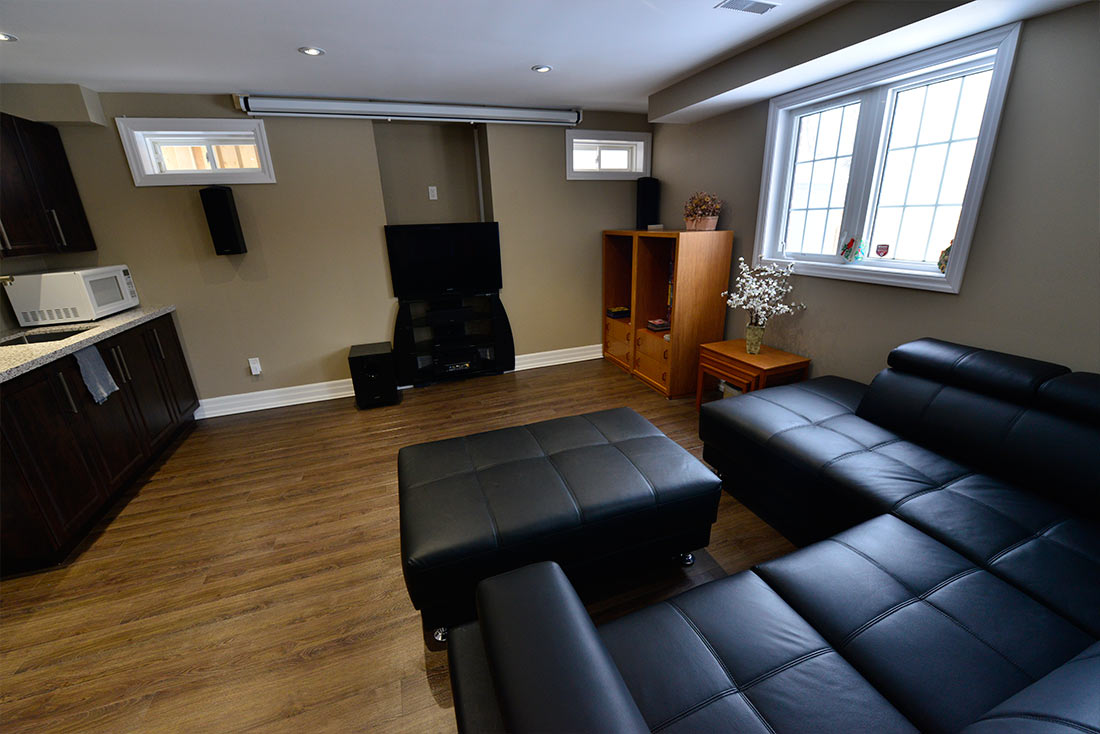 The family room, the kitchenette and the TV in a finished basement by Harmony Basements