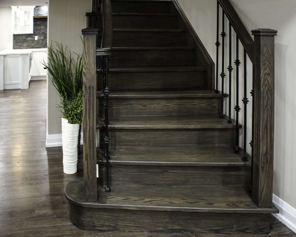 A finished basement in Toronto: the curved oak stair with iron pickets, by Harmony Basements