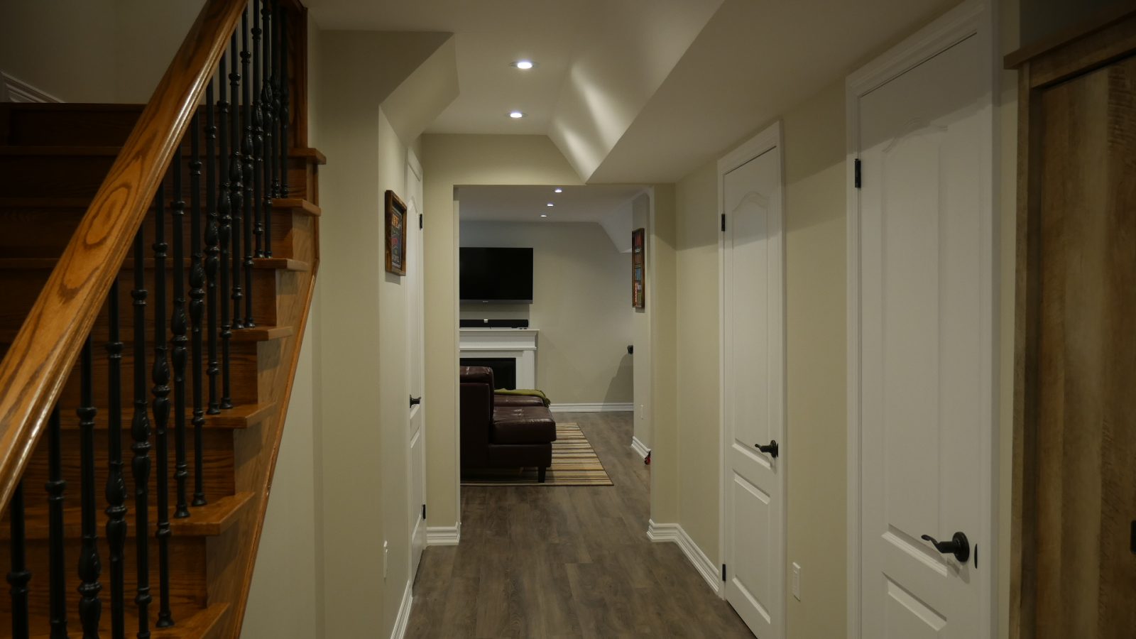 The new open staircase, its railing and pickets in a finished basement by Harmony Basements
