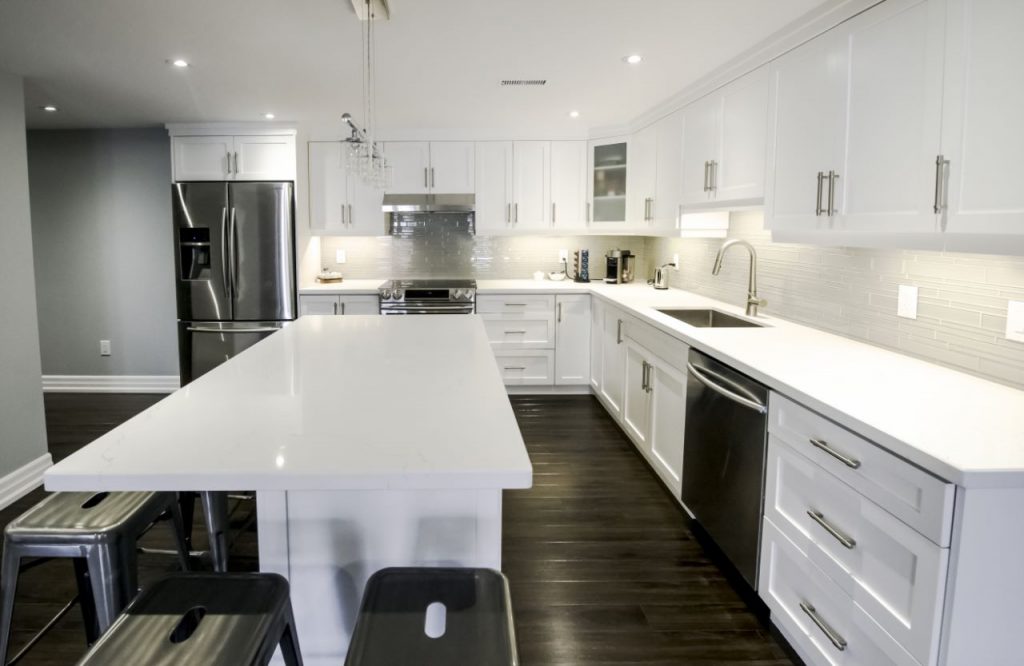 White basement kitchen with a quartz island and stainless steel appliances