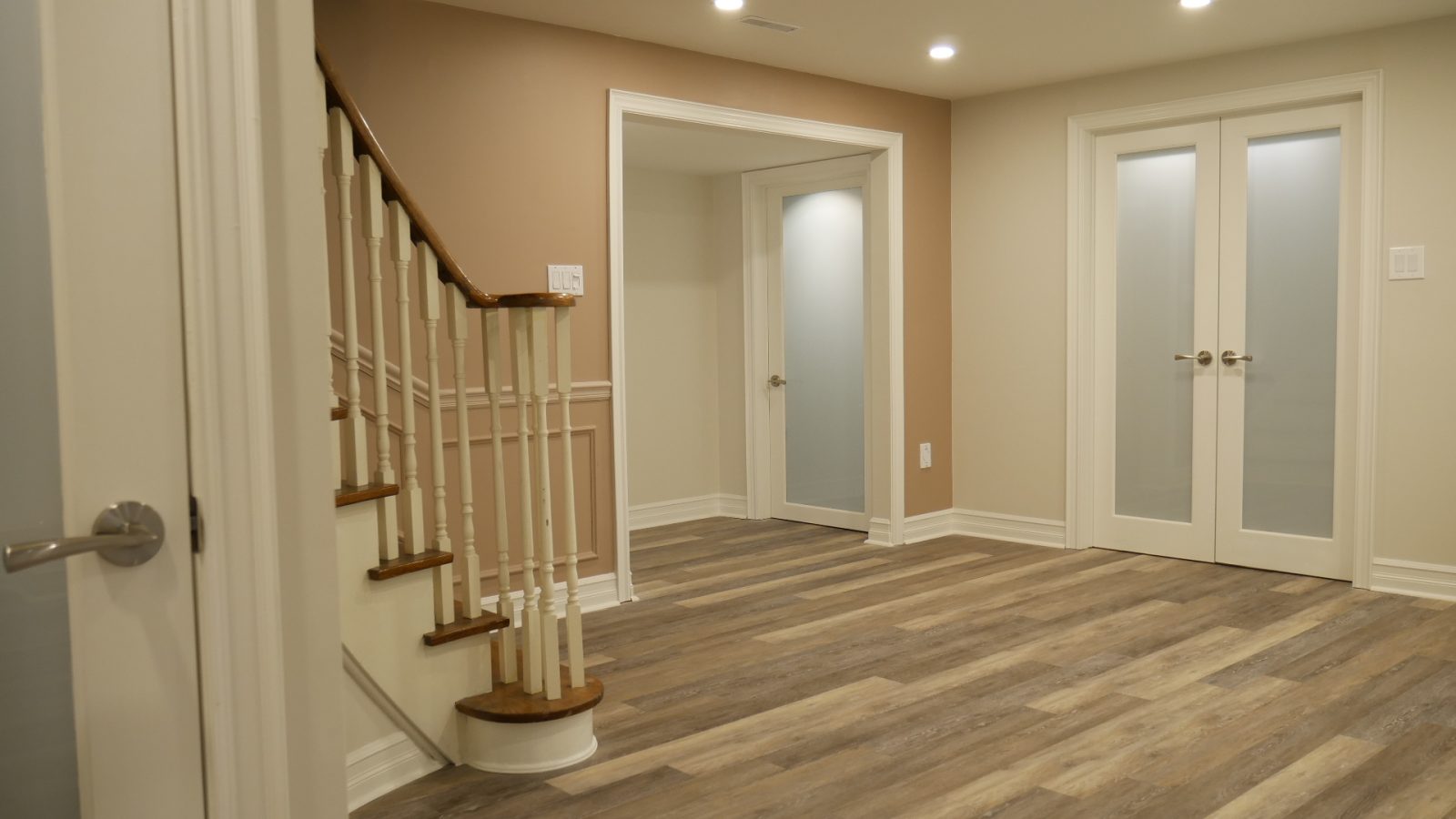 The staircase and the frosted-glass doors in a finished basement by Harmony Basements