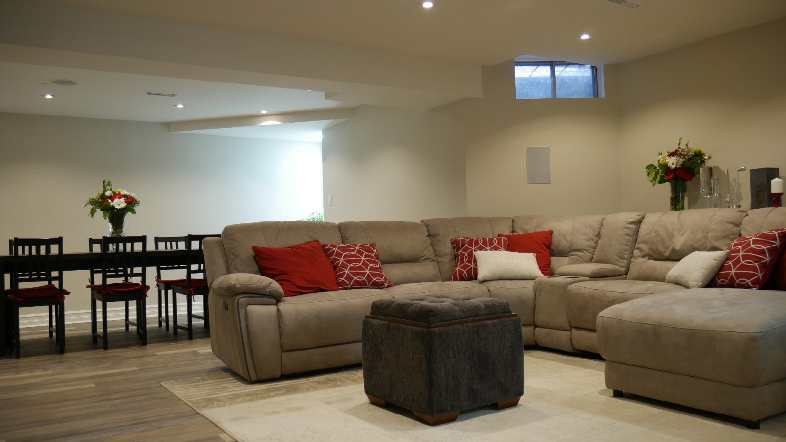L, by Harmony Basementsarge open space basement with floor carpet and red pillows on the sofa basement finishing innisfil