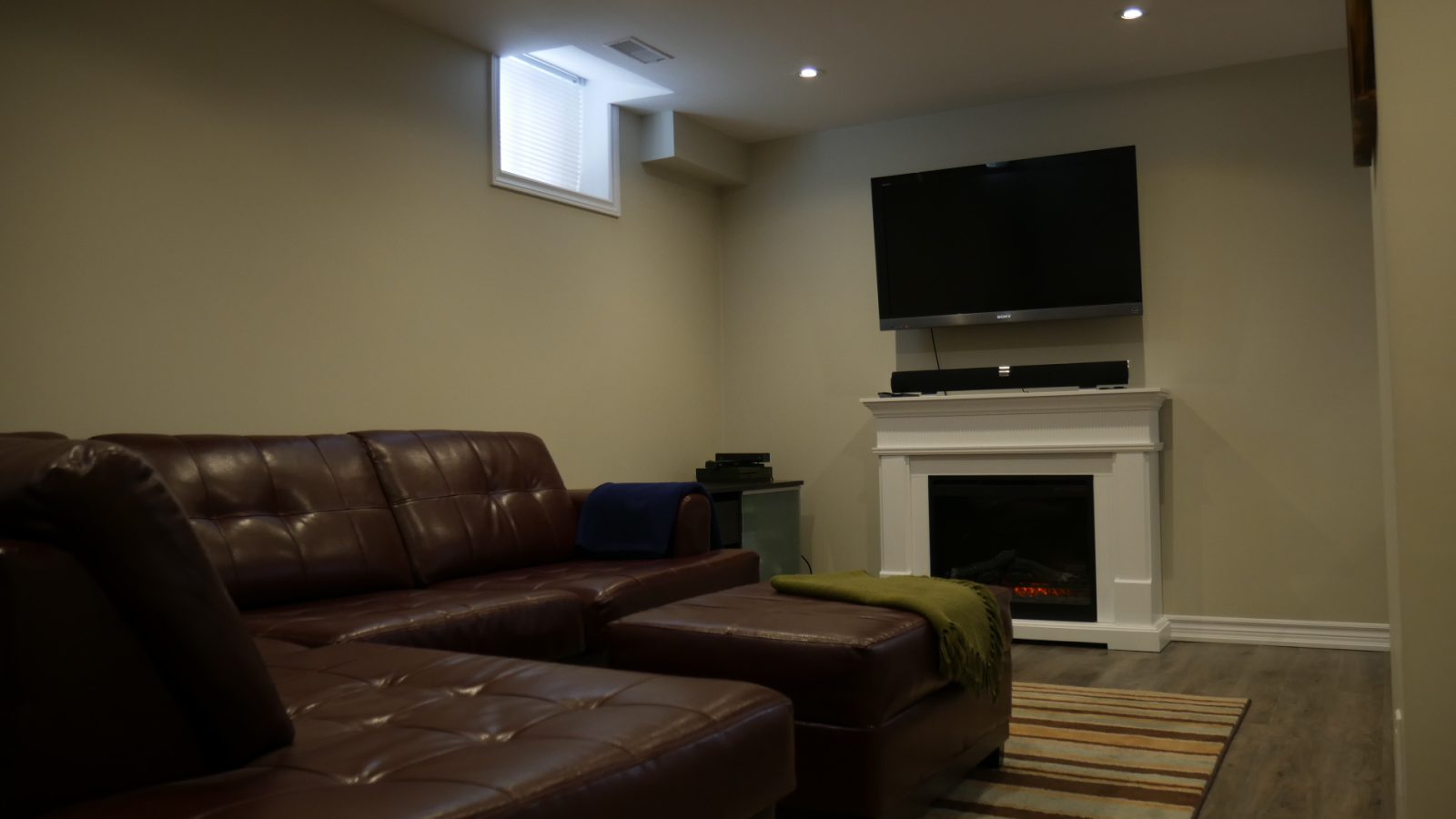 The family room and the fireplace in a finished basement by Harmony Basements