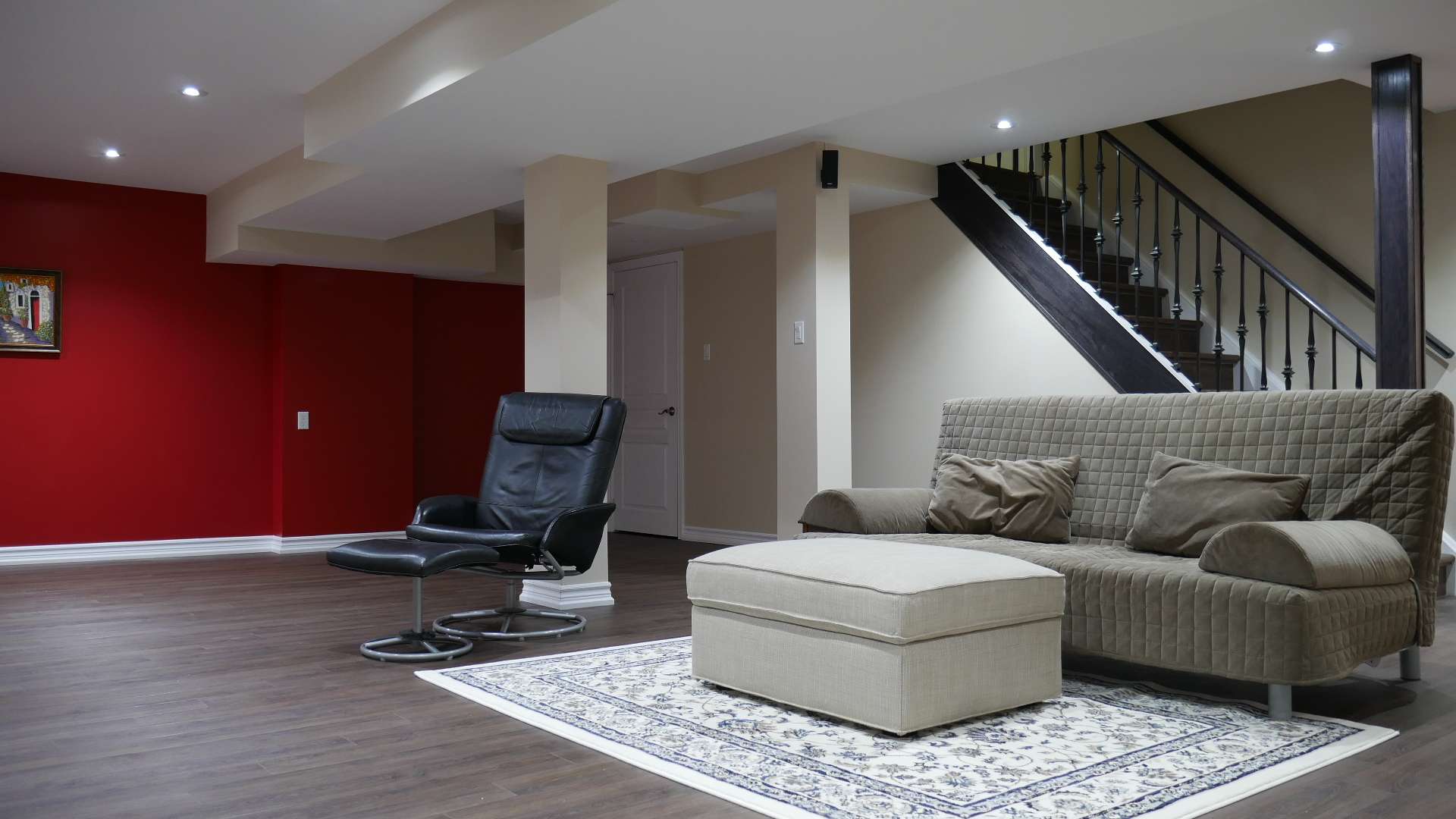 The recreation room, the red accent wall and the staircase in a finished basement by Harmony Basements