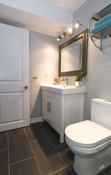 The bathroom vanity and a rustic mirror in a finished basement in Maple by Harmony Basements