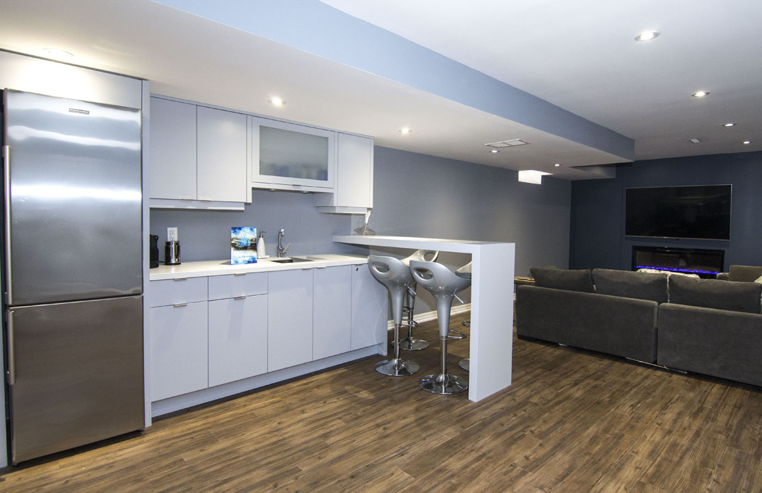 The wet bar and its breakfast peninsula in a finished basement in Maple by Harmony Basements