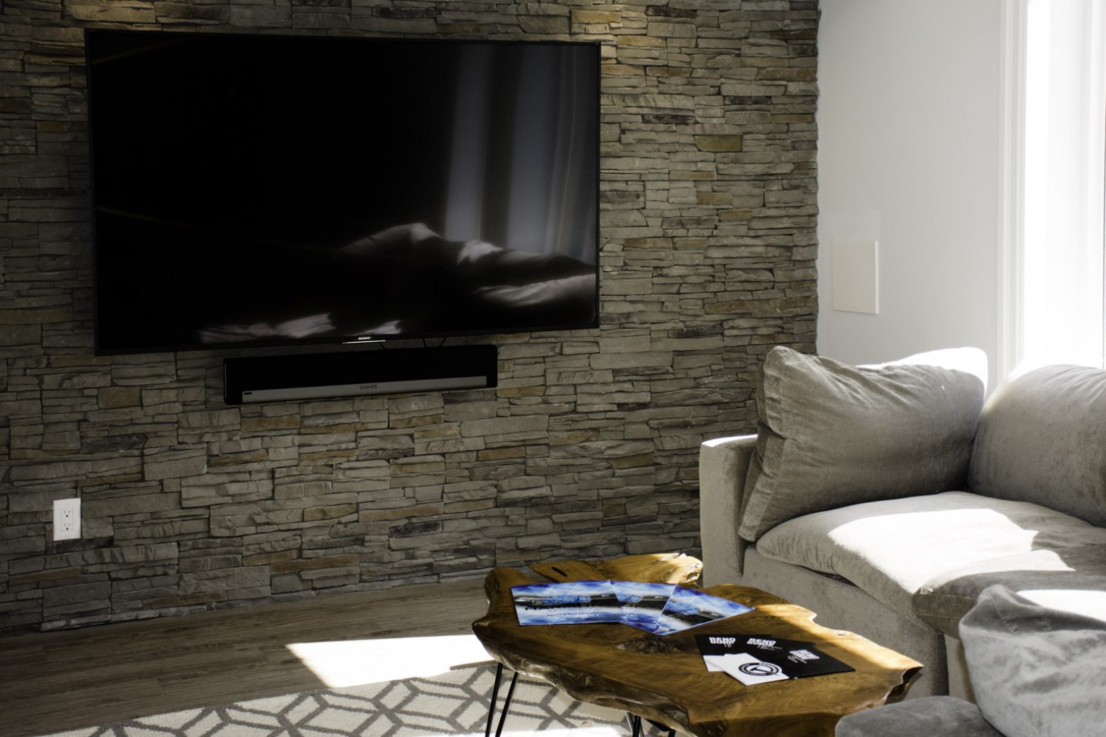 The stacked-stone TV wall in a finished Harmony walkout basement in Halton
