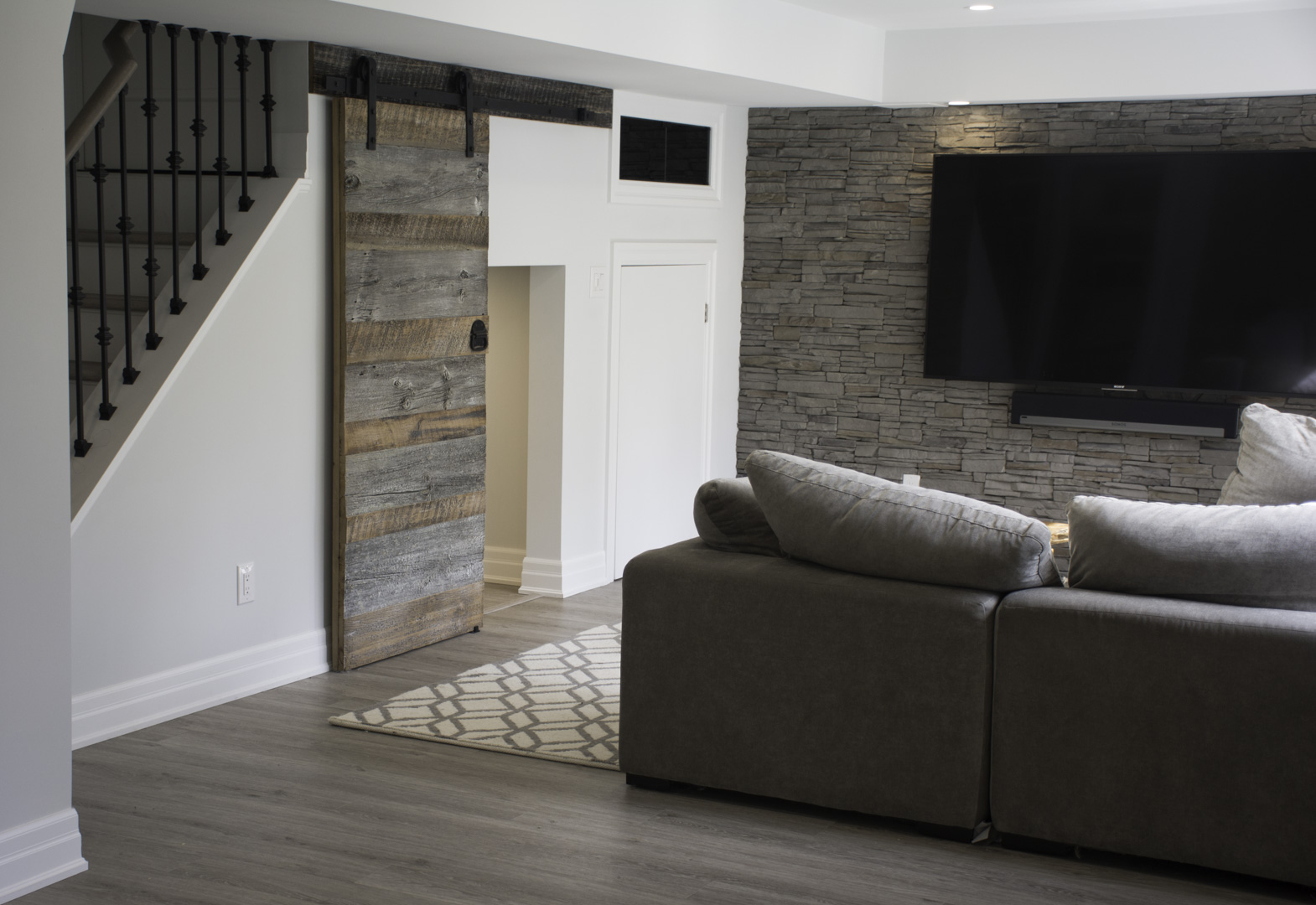 The staircase, the barn door and the stone wall in a finished basement in Oakville by Harmony Basements