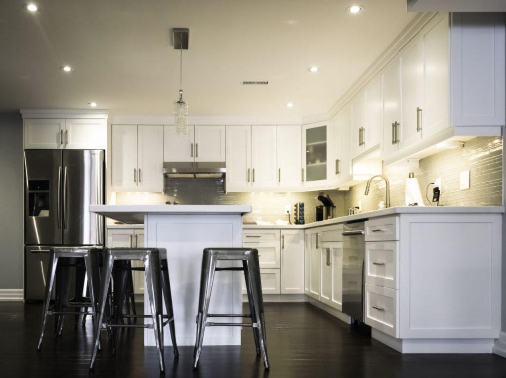 L-shaped white basement kitchen with an island and bar stools