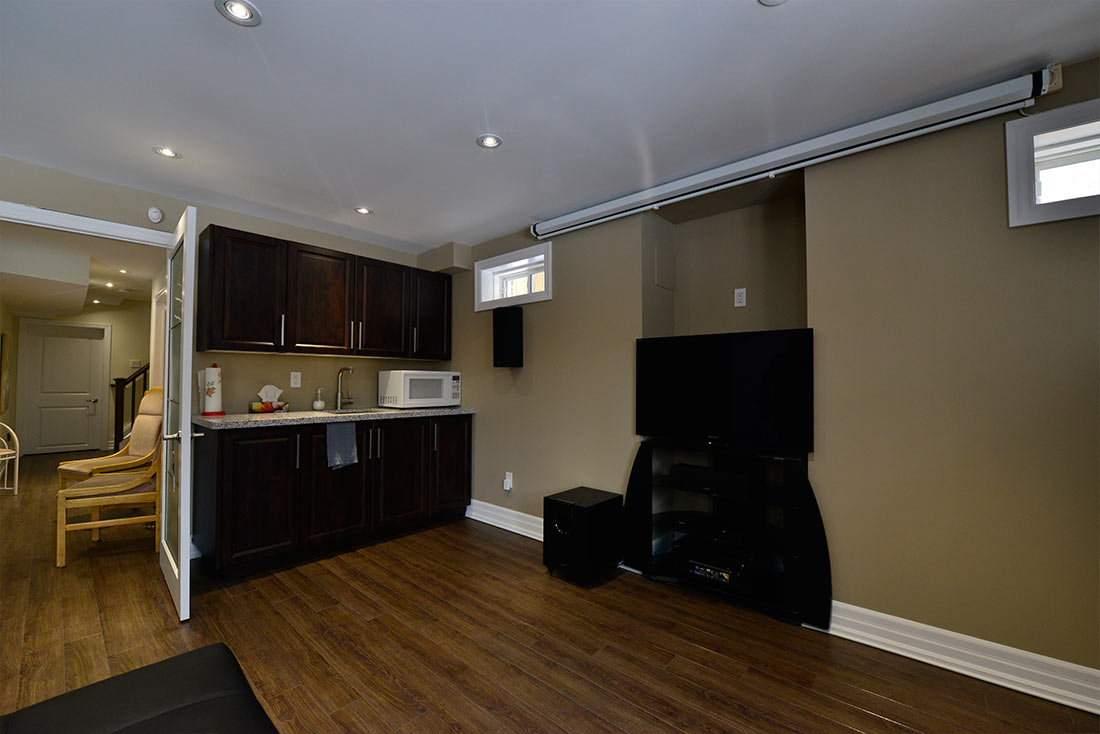 Basement entertainment area in Brampton: the TV wall beside the kitchenette &mdash; a walkout basement by Harmony Basements