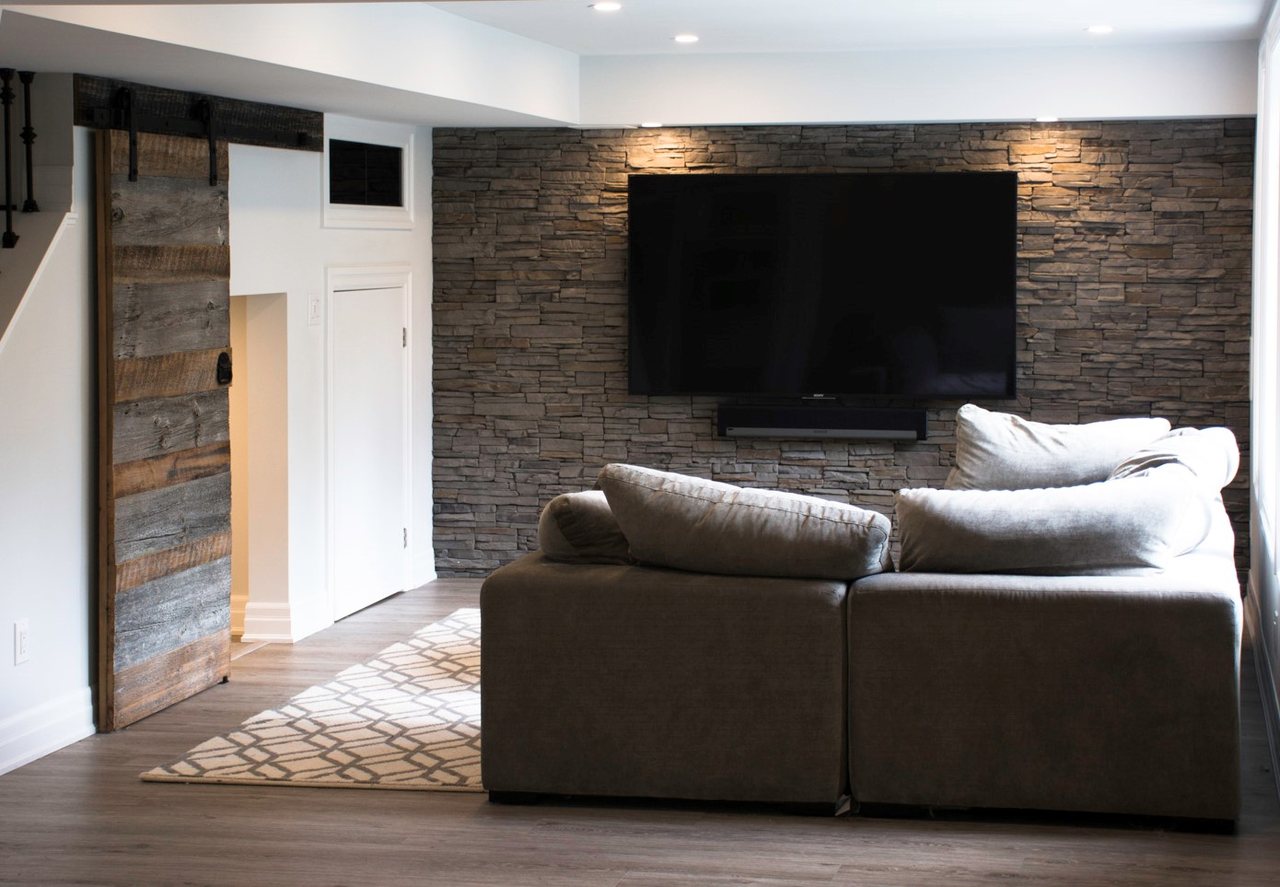 Basement family room ideas for Innisfil: a stacked-stone TV wall, a rustic barn door and the sectional &mdash; a walkout basement we built in Oakville
