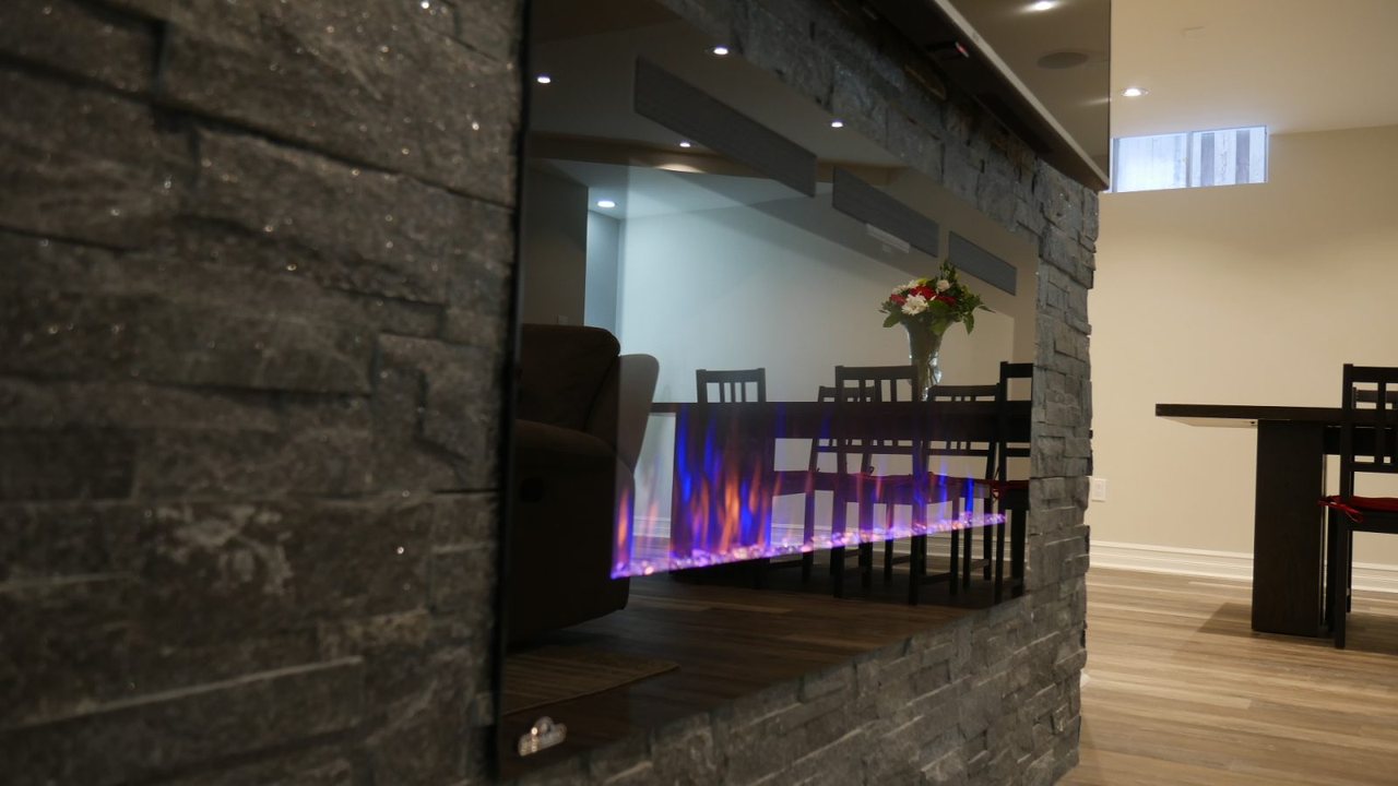 Basement fireplace in Markham: a natural stone fireplace, open to the dining area &mdash; a finished basement by Harmony Basements