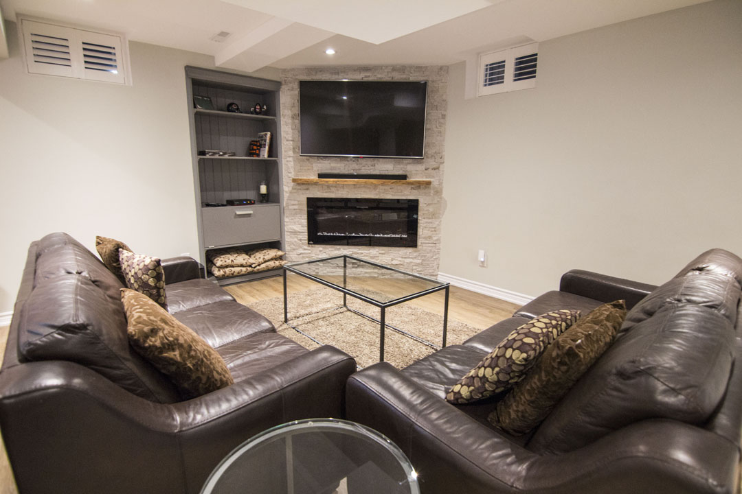 Basement media wall in Kleinburg: the built-in media wall with the natural stone fireplace, by Harmony Basements