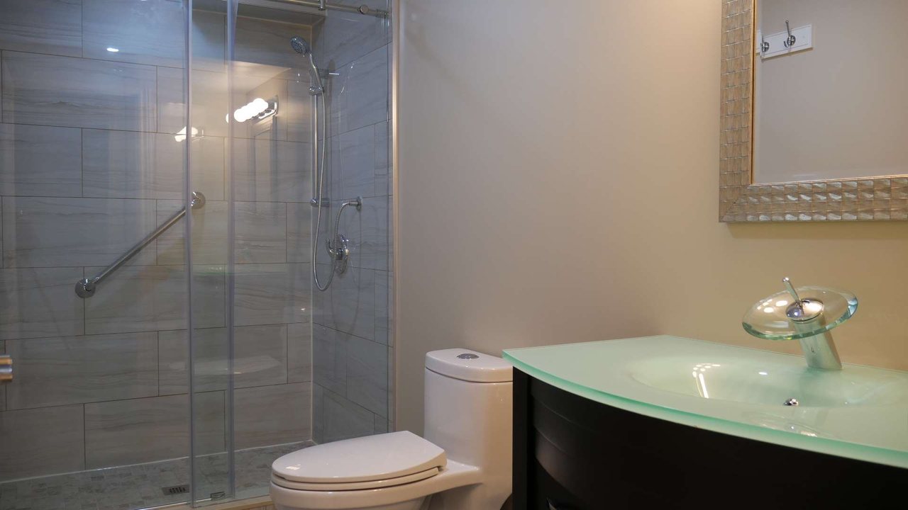 Basement washroom in Milton: a glass shower and a glass-top vanity &mdash; a finished basement by Harmony Basements