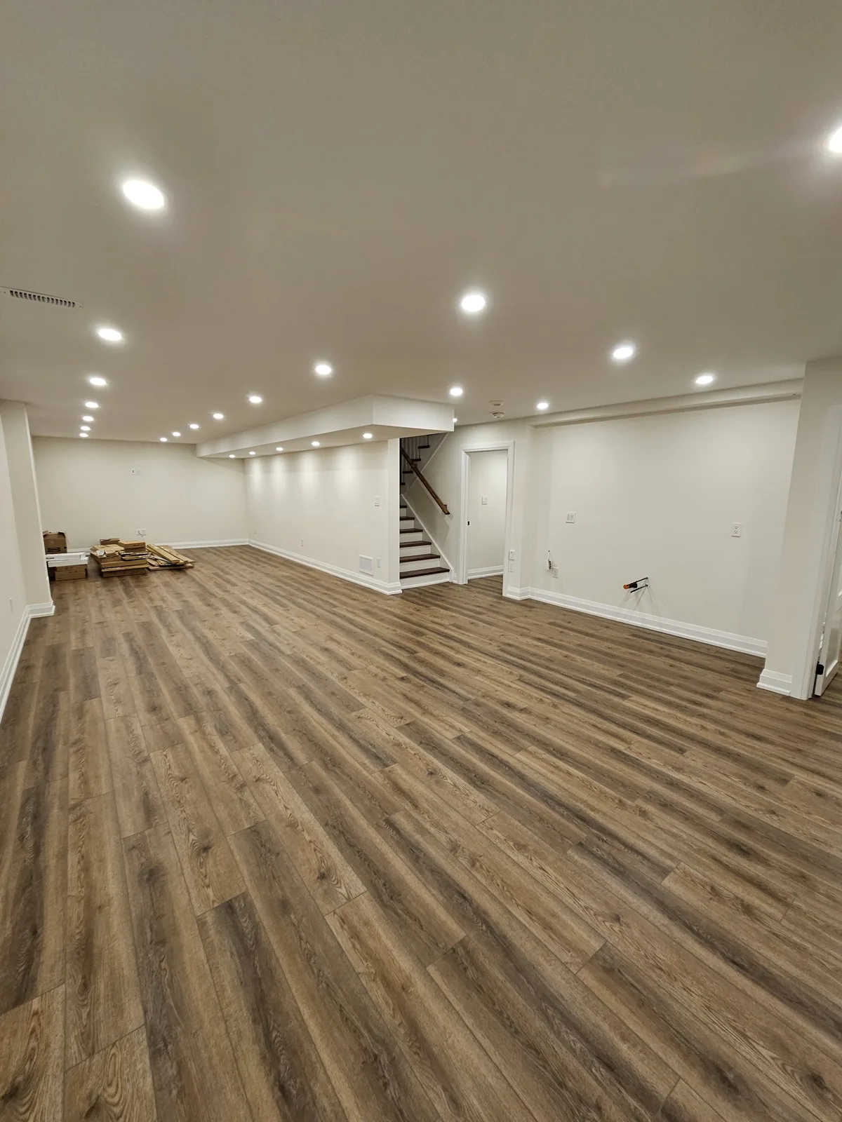 Open-concept basement in Ancaster, Hamilton: the open recreation area and the stairs, by Harmony Basements